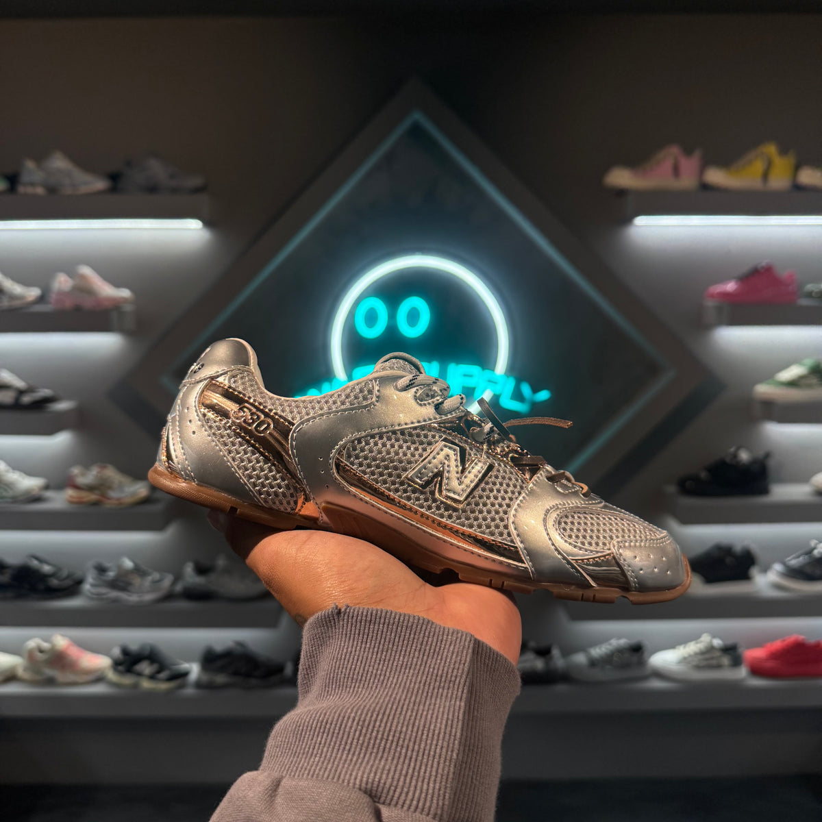 New Balance 530 Miu Miu Silver Gold - tenis plateado y dorado en la mano, vista lateral